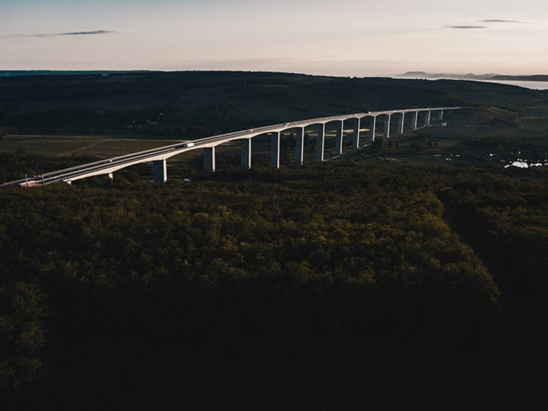 An aerial shot of a steel arch bridge built in a forest